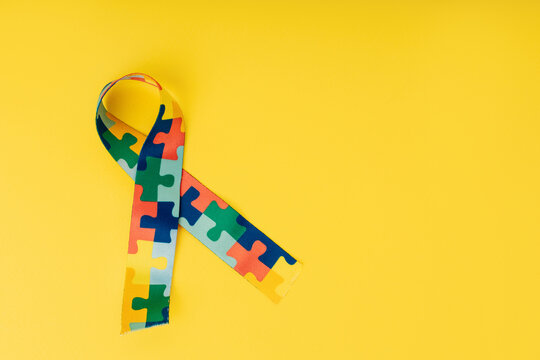World autism awareness and pride day. Puzzle pattern ribbon on a yellow background