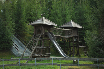 Fototapeta na wymiar Wooden playground with slide in Carpathian mountains