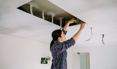 Woman preparing extractor hood installation on kitchen ceiling