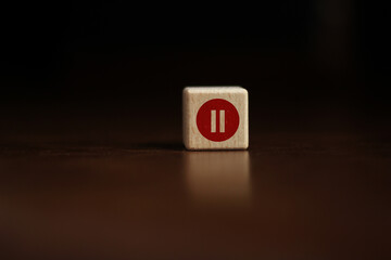 red circle with pause button or icon on wooden cube background with dark background