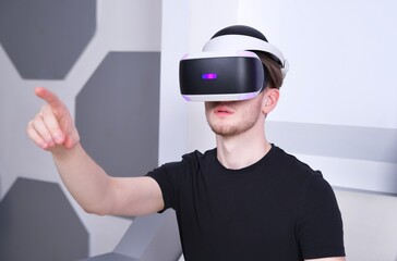 Happy young man, guy using, wearing a modern device virtual reality headset mask or 3D, AR, VR glasses, playing the game, pointing with hand, finger to camera. People and technology metaverse concept.