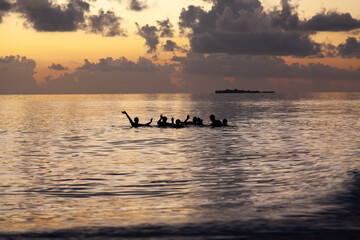 Group of friends enjoying a bath in the island lagoon at sunset