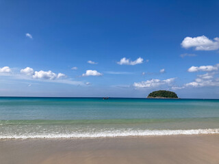 fisherman's boat in the deep blue sea with a green hill, blue sky, white cotton clouds, and sea waves on the beach