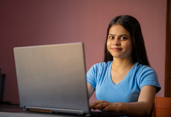 Portrait of a beautiful and young Indian woman working on her laptop
