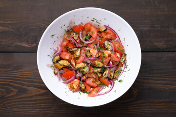 Salad with mussels and tomatoes and red onion in white plate on wooden table. Concept of healthy diet food. Flat lay.