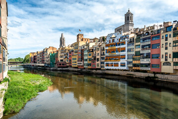 Colorful yellow and orange houses reflected in water river Onyar, in Girona, Catalonia, Spain. Church of Sant Feliu and Saint Mary Cathedral at background.