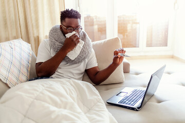 Sick young man blowing his nose talking to a doctor. Sick male complaining during video call with...
