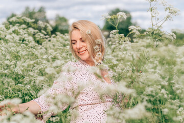 Happy young blonde pregnant woman  in a pink dress in a meadow on a summer day.Summer,pregnancy and...