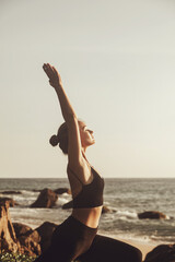 Fototapeta na wymiar Young woman does yoga for healthy lifestyle on sea beach