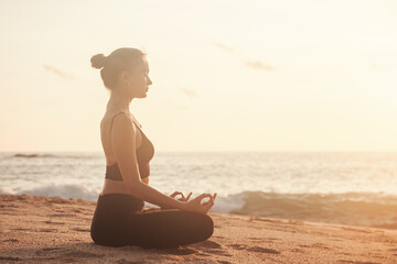 Fototapeta na wymiar Young woman does yoga for healthy lifestyle on sea beach