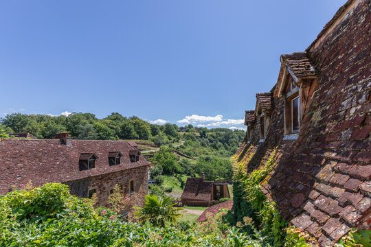 Small medieval settlement near castle walls of fortress Chateau de Castelnau-Bretenoux with tiled roofs and red stonework. Prudhomat, Lot, Occitanie, France