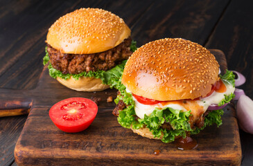 Close-up of delicious homemade burgers on a black wooden table. Delicious freshly prepared chicken, pork, or beef hamburgers.