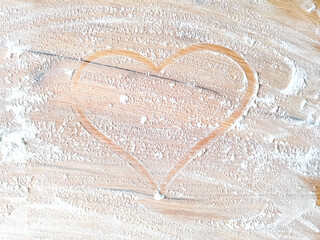 Heart drawn by finger with white flour on wooden table . Free space for text. View from above. Top view