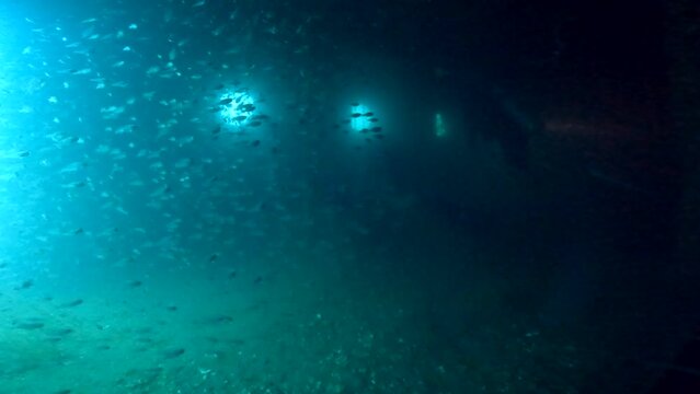 Under water scuba diving film - Inside the wreck of HTMS Sattakut - with divers with flash lights and plenty of small fish - Southern ThailandSouthern Thailand