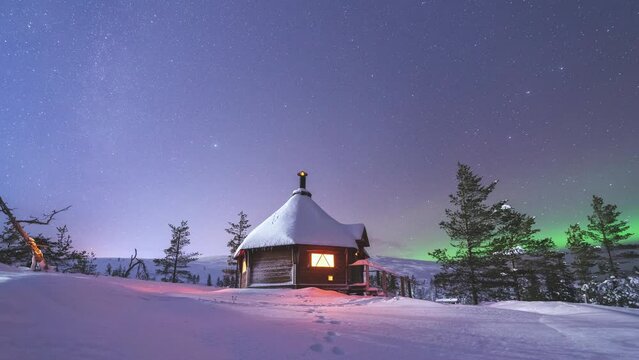 Timelapse of a wilderness cabin in winter night under starry sky and northern lights in Lapland, Finland