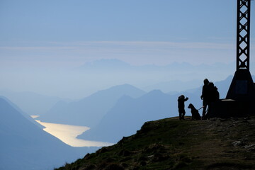 Family silhouette with dog on mountain ridge at dusk