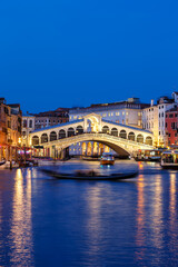 Fototapeta na wymiar Venice Rialto bridge over Canal Grande with gondola travel traveling holidays vacation town portrait format at night in Italy