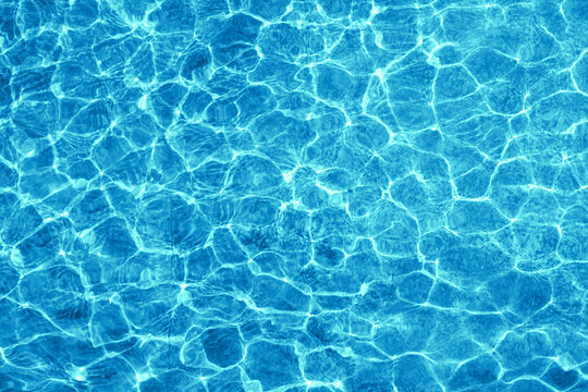 Water in fountain or pool shimmering in the sun. Rippling water surface with sun glare.