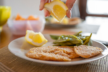 Hand queezing lemon on vegan chickpea cutlet.