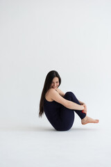 Obraz premium Young beautiful woman practicing yoga on a white background. Young beautiful girl doing exercises at home. Harmony, balance, meditation, relaxation, healthy lifestyle concept 