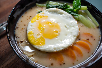 Close up of Japanese Ramen with sunny side egg topping with isolated wooden table background