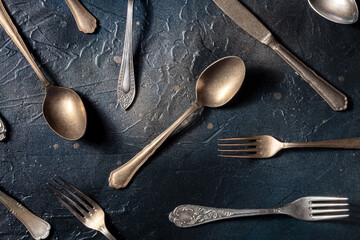 Cutlery pattern. Spoons, forks, and knives. Modern tableware on a black slate background, shot from the top, a flat lay