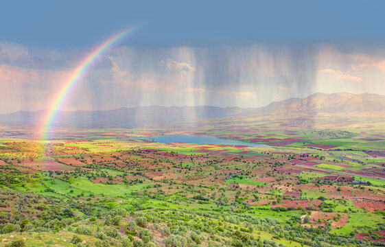 Beautiful blue lake landscape with a view of the mountains and a green valley and a rainbow in the clouds