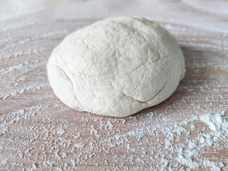Fresh raw dough on wooden table covered with flour. Top view