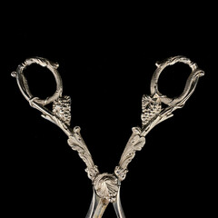 antique silver scissors with engraving. vintage hair clipper with flower pattern on black isolated background