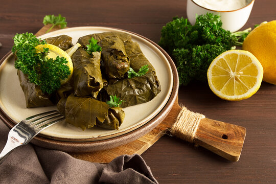 Dolma, cabbage rolls, grape leaves with filling, white sauce, lemon and herbs, rustic, selective focus, no people,