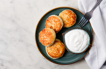 Fried, Cottage cheese pancakes, with sour cream, Cheesecakes, on a marble table, top view, no people.