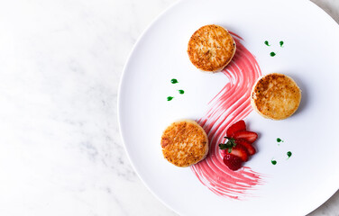 Cottage cheese pancakes, on a white plate decorated with sauce, fresh strawberry berry, close-up, no people,