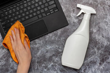 Cleaning a laptop keyboard with a rag and cleansing spray bottle mock-up