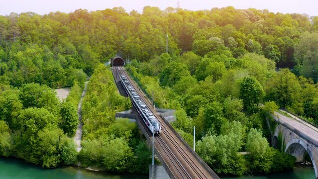 Tunnel entrance of high speed train track - aerial view, drone footage.  train at rural scene in summer. The train rides through rural countryside in sunrise. train rides along the beautiful summer. 