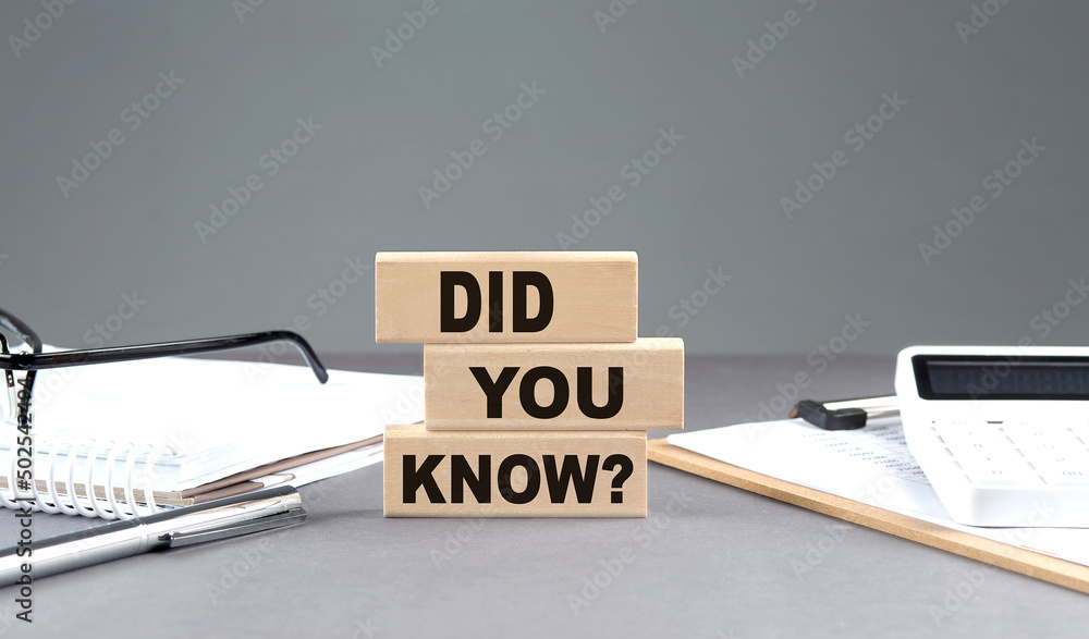 Poster did you know text on wooden block with notebook,chart and calculator, grey background