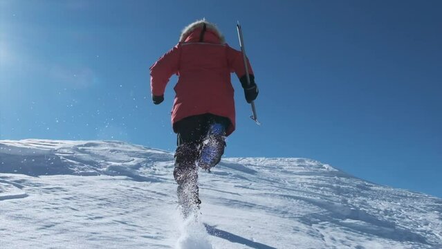 Man runs along steep snowy slope from behind in slow motion
