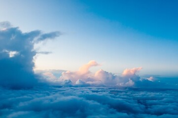 View of the pre-sunset cloudy sky through the porthole of the aircraft. Blue summer sky with white clouds. Clear sky overhead.