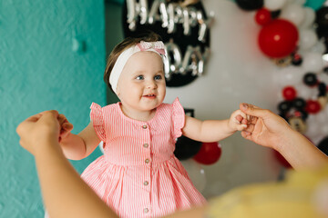 beautiful little one-year-old girl in a pink dress eats a lollipop. the child smeared himself with candy. kids love sweets