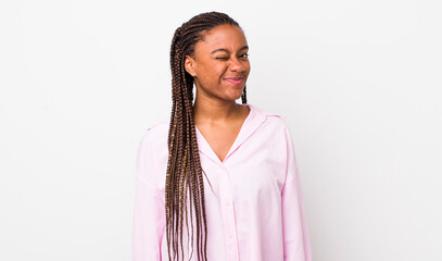 afro pretty woman looking happy and friendly, smiling and winking an eye at you with a positive...