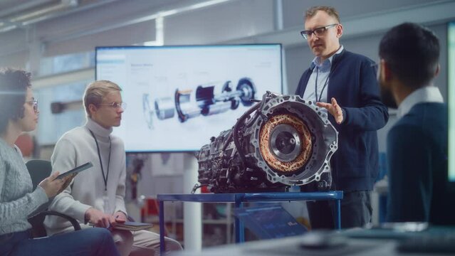 Diverse Specialists Gathering around Engine and Discussing it with Male Chief Engineer at Seminar. Research, Development, Visualisation, Digitalisation of Green Electric Energy Concept. Slow Motion