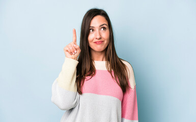 young adult pretty woman feeling like a genius holding finger proudly up in the air after realizing...
