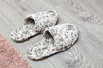 Knitted slippers stand on a gray wooden floor