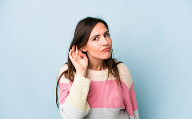 young adult pretty woman looking serious and curious, listening, trying to hear a secret...