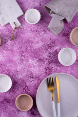 Fototapeta na wymiar Plate, bowls and cutting board on lilac background