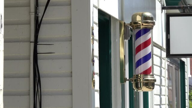 Barber pole revolves on clapboard building with coax cables.