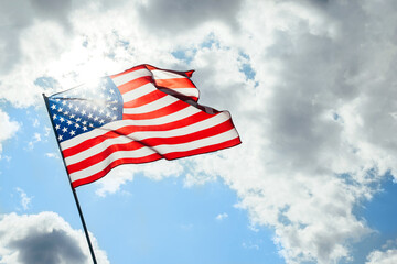 USA America flag waving in the wind over cloudy sky low angle view.
