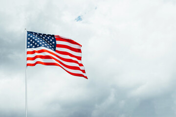 USA America flag waving in the wind over cloudy sky low angle view.