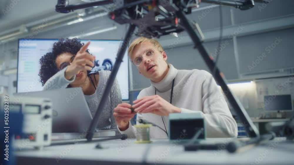 Aufkleber Male Engineer Put Processor at Drone while Female Programming at Laptop. High Tech and Unmanned Aerial Vehicle Concept. Portrait Medium Slow Motion
