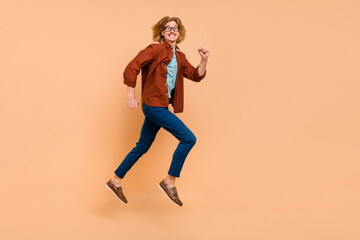 Fototapeta na wymiar Full length body size view of attractive cheerful motivated guy jumping running isolated over beige pastel color background