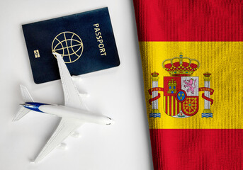 Flag of Spain with passport and toy airplane. Flight travel concept 